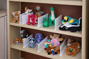 Shelf with various stuffed animals and small books on a wooden shelf.