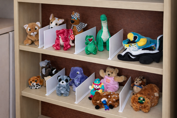 Shelf with various stuffed animals and small books on a wooden shelf.