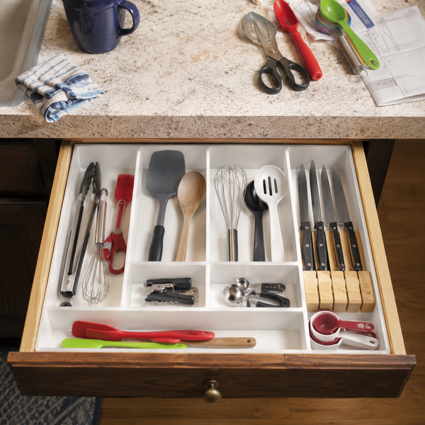 Kitchen drawer with organized utensils on a countertop.